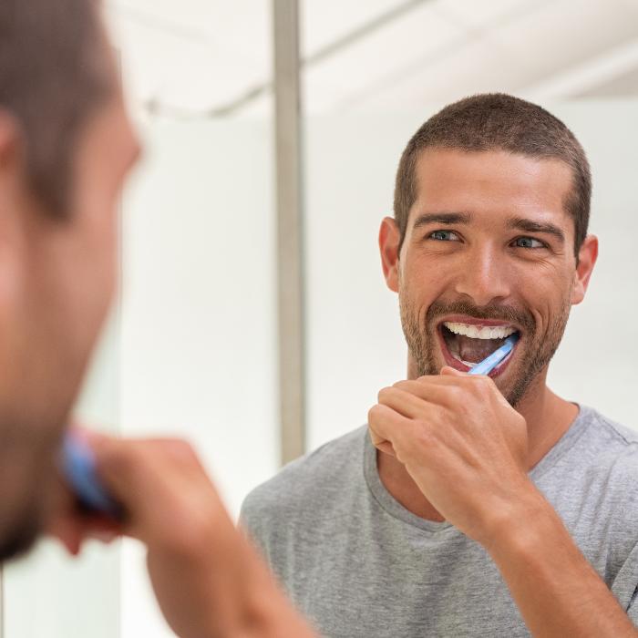 Male brushing teeth after dental implants